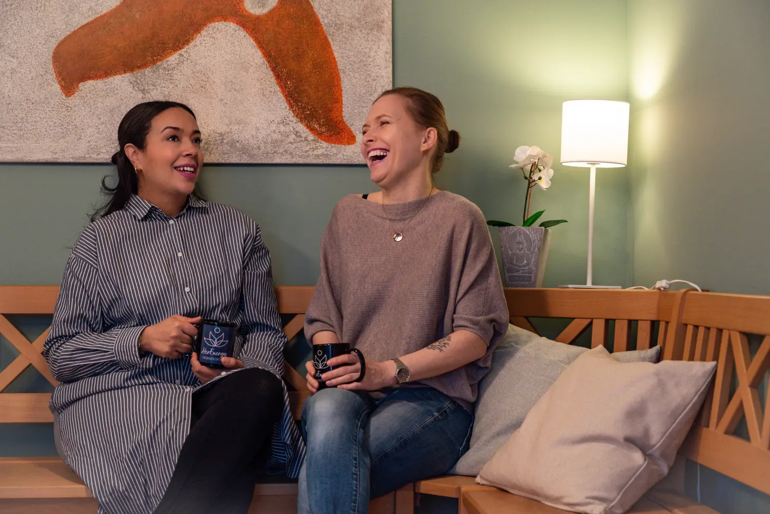 Thouraya und Wanda, die auf der Bank sitzen und Kaffeetassen halten