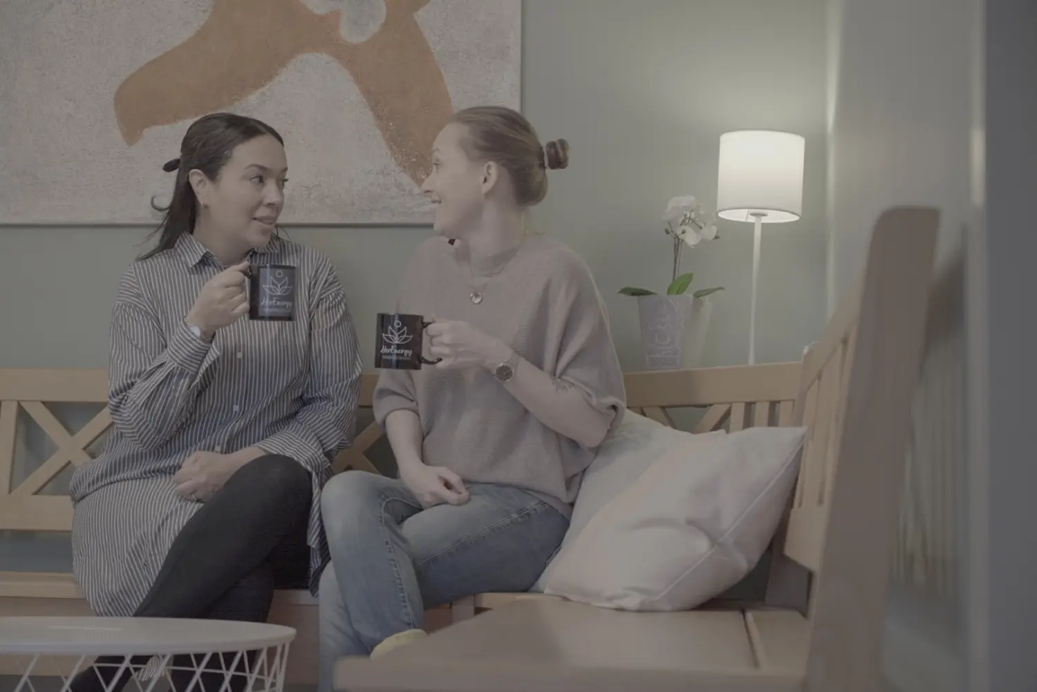 Thouraya und Wanda, die auf der Bank sitzen und Kaffeetassen halten